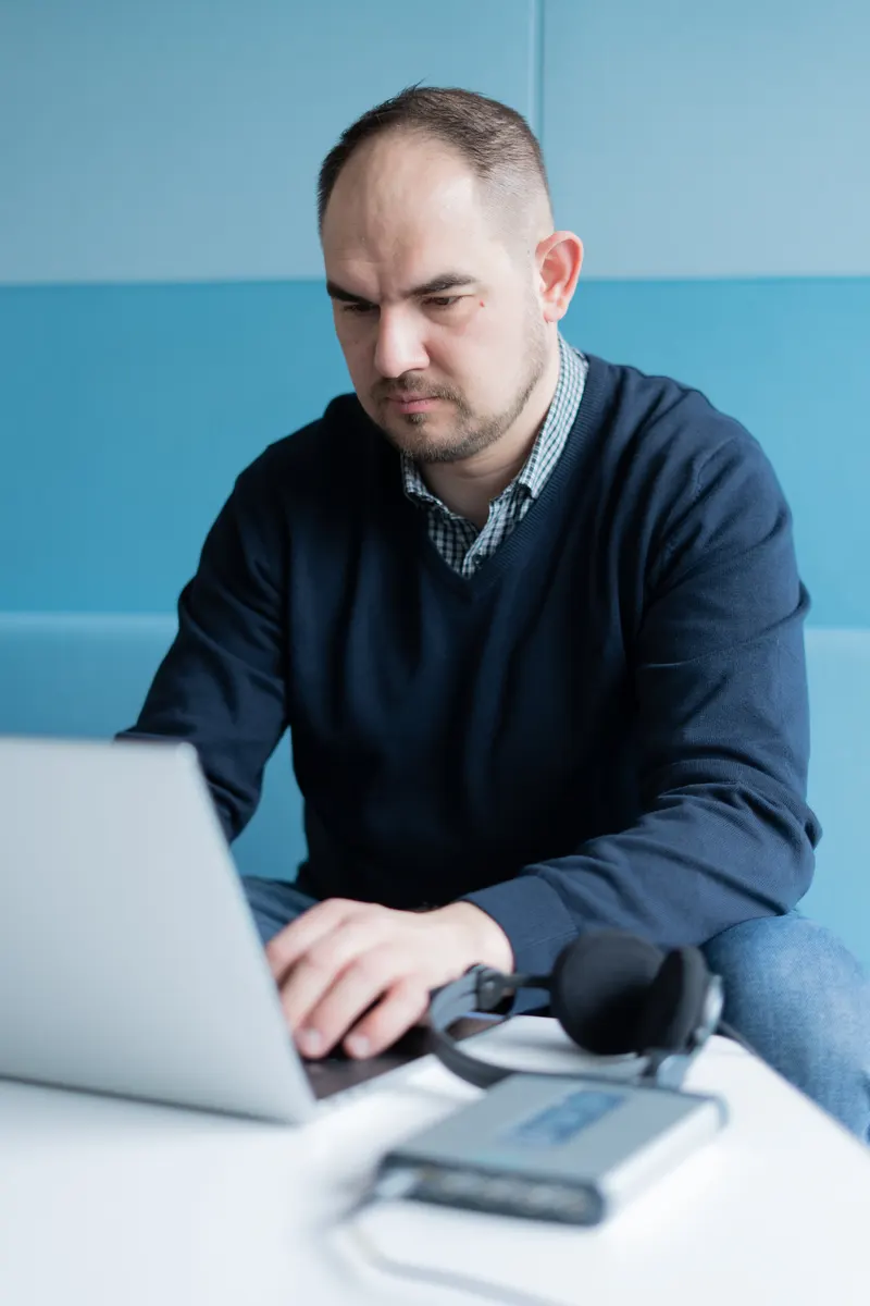 Roman Sereinig working on a laptop, with headphones and the measurement system next to it.